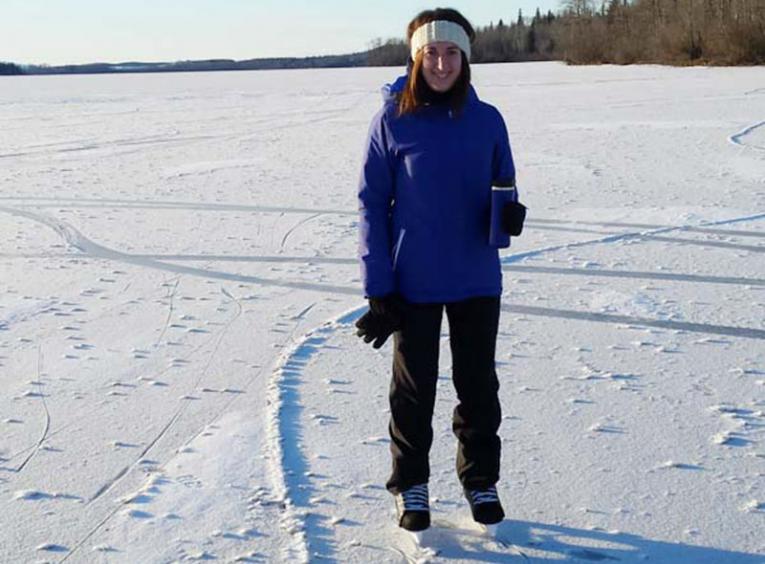 Woman standing on a frozen lake with ice skates on.