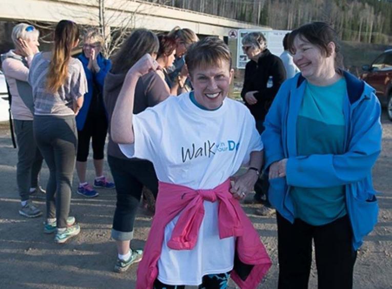 A woman flexing and smiling while participating.