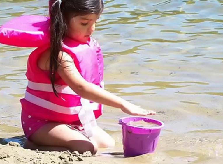 Girl wearing life-jacket at the beach.