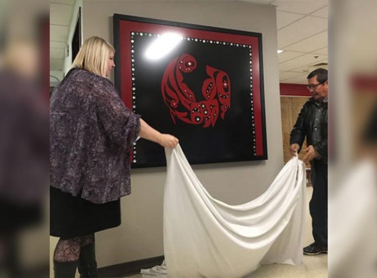 Curtain being pulled off of art piece.
