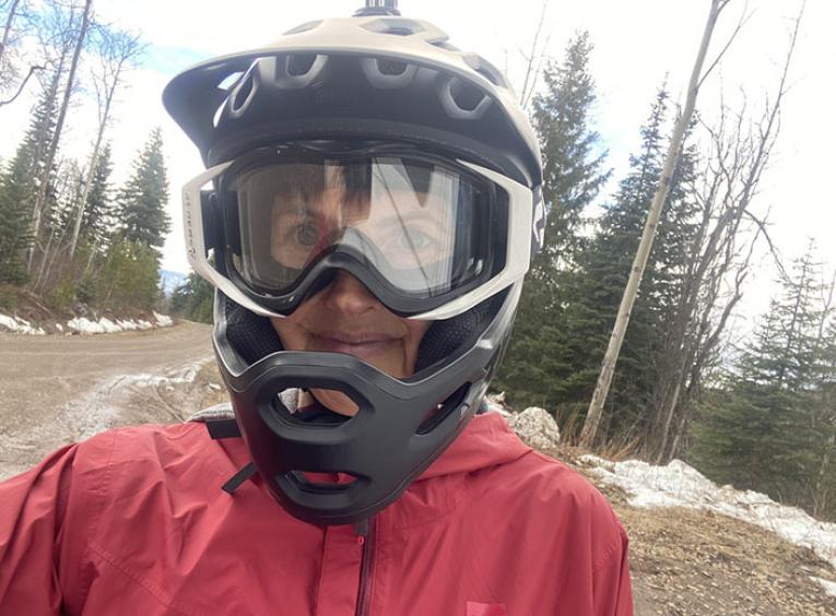 Person wearing a helmet and goggles on muddy path. 