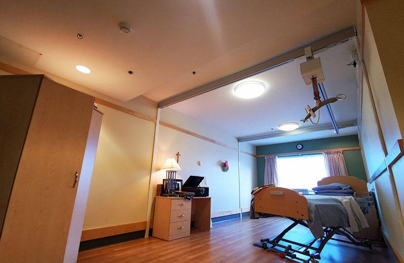 A bed in a long term care facility with a mechanical lift over it. 